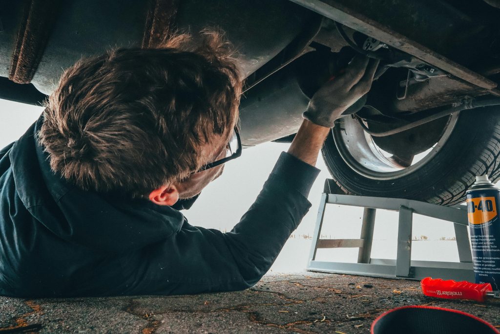 pexels-photo-2244746-2244746-1 Mechanic skillfully repairing car undercarriage in outdoor setting with tools.